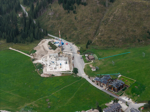 Aerial view of the new skylift to Rolle Pass construction site, with concrete foundations and a crane, in San Martino di Castrozza, Trentino-Alto Adige, Italy.