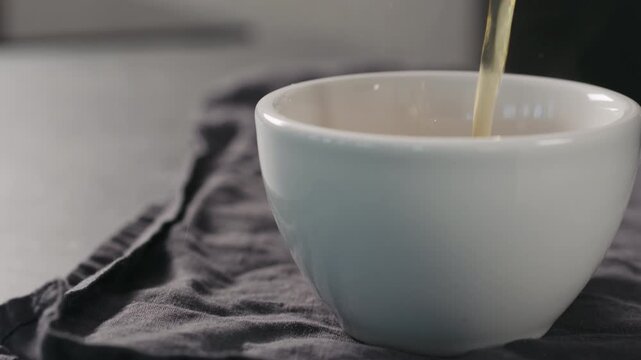 Slow motion pour black tea in white cup closeup with copy space