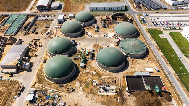 Aerial view of a biogas plant featuring large green dome-shaped digesters, industrial infrastructure, and storage tanks situated in an industrial zone in Sabac, Vojvodina, Serbia.