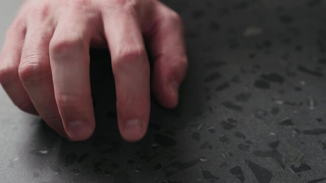 Slow motion closeup man finger tapping on terrazzo countertop