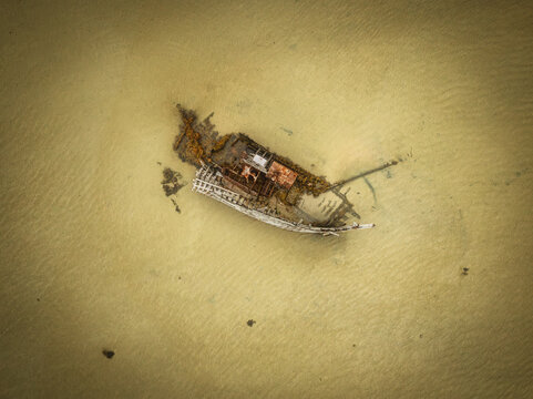 Aerial view of the Bunbeg Beach Shipwreck resting on the sandy tidal flats of the coast, County Donegal, Ireland.