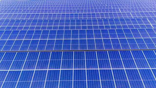 Aerial view of a large solar farm with rows of blue photovoltaic panels capturing sunlight in a rural field in Sabac, Vojvodina, Serbia.