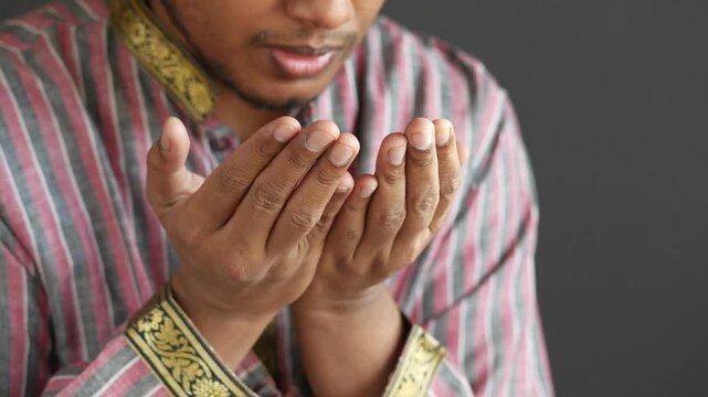 Man with hands cupped in prayer, showing devotion and seeking blessings on dark background