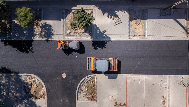 Aerial view of road construction with two steamrollers paving fresh asphalt on a city street in Pancevo, Vojvodina, Serbia.