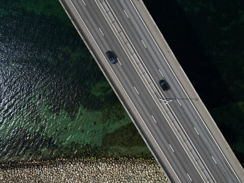 Aerial view of the Oresund Bridge with cars driving across the multi-lane highway above the clear sea and rocky coastline in Malmo, Skane County, Sweden.