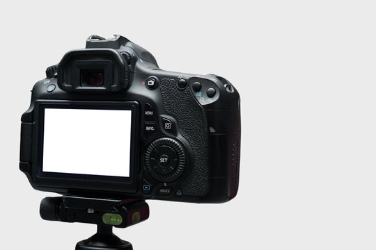 Digital Single Lens Reflex Camera On Tripod Against Neutral Background