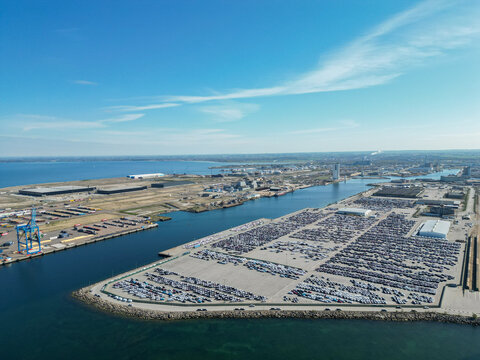 Aerial view of the Port of Malmo showing extensive car storage lots, industrial infrastructure, shipping cranes, and the surrounding coastline in Malmo, Skane County, Sweden.