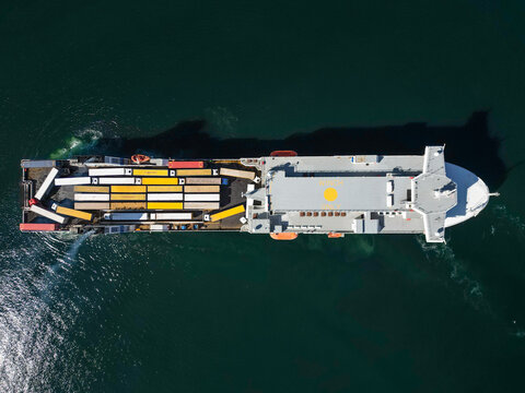 Aerial view of a large ferry transporting numerous semi-trucks and trailers across the calm dark blue sea in Malmo, Skane County, Sweden.