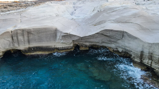 Aerial view of the white volcanic rock formations and turquoise waters of Sarakiniko beach in Milos, Greece.