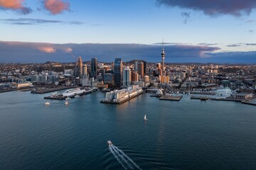 Obraz premium Aerial view of boats cruising Waitemata Harbour with Auckland CBD skyline and Sky Tower at sunset in Auckland CBD, Auckland, New Zealand.
