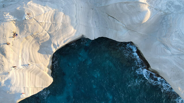 Aerial view of Sarakiniko beach with unique white volcanic rock formations and turquoise waters in Milos, Greece.