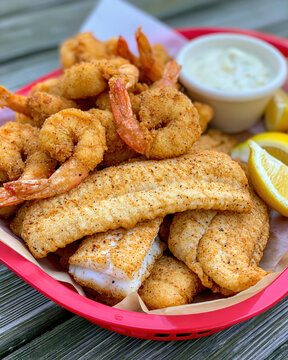 Fried catfish fillet fried shrimp cornmeal coating seafood basket tartar sauce lemon wedge golden crust crispy texture southern food dinner plate food closeup shellfish fish fillet breaded seafood