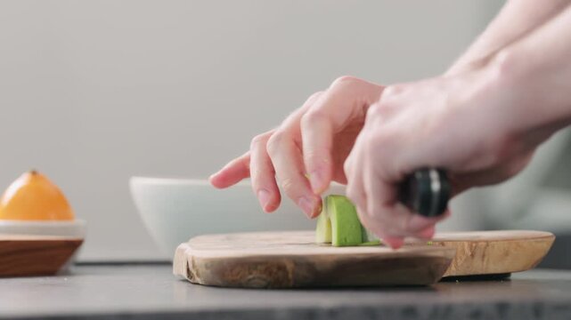 Man slicing ripe avocado on kitchen countertop side view
