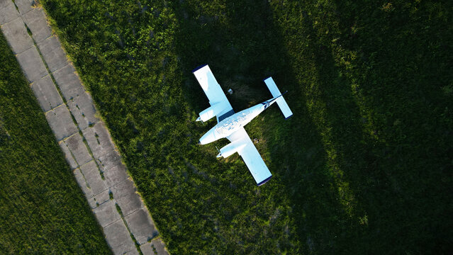 Aerial view of a small white airplane parked on the grass next to a concrete runway in Lisicji Potok, Belgrade, City of Belgrade, Serbia.