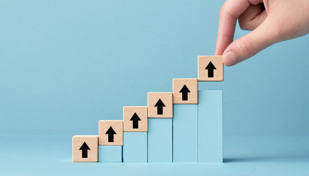 A hand placing a wooden block with upward arrow on a rising chart made of blocks