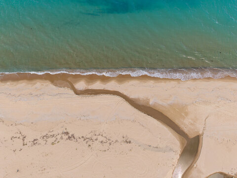 Aerial view of Kara Dere beach with a stream flowing into the turquoise Black Sea, sandy coastline, and gentle waves in Byala, Varna, Bulgaria.