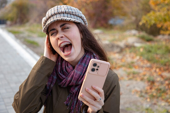Young Caucasian woman holding smartphone and celebrating unexpected success. Joy, achievement, and positive emotions concept in a modern lifestyle setting.