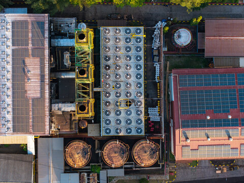 Aerial view of the PLTDG Pesanggaran Diesel and Gas Power Plant featuring solar panels on rooftops, rows of cooling fans, and large storage tanks, Denpasar Selatan, Bali, Indonesia.