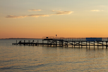 Obraz premium Wooden Pier extending into Sea at Sunset Sky