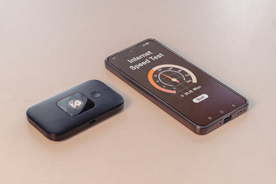 High speed connectivity on the go. 5G pocket wifi router and a smartphone running internet speed test.