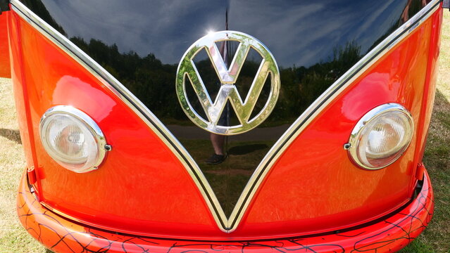 Classic red Volkswagen Kombi van with iconic chrome emblem and round headlights