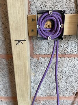 Electrical wiring installation with purple cable neatly coiled inside a metal junction box