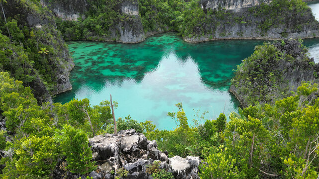 Aerial view of Star Lagoon featuring turquoise waters surrounded by lush green karst islands and rocky cliffs in Raja Ampat, Papua Barat Daya, Indonesia.