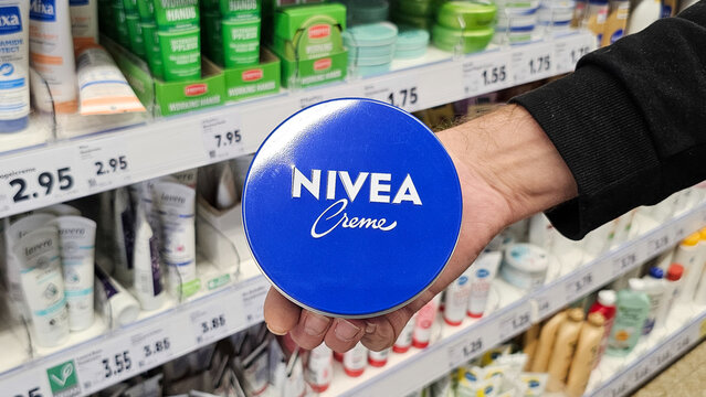 Hand holding nivea creme tin in a supermarket aisle