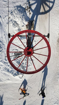 Aerial view of the red ski lift wheel at Divcibare Ski Resort with skiers gliding on the snow-covered slopes in Divcibare, Kolubarski okrug, Serbia.