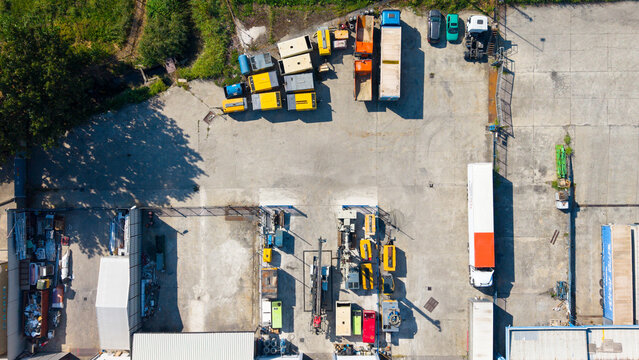 Aerial view of portable air compressors and various industrial equipment parked in a concrete yard in Milan, Lombardy, Italy.