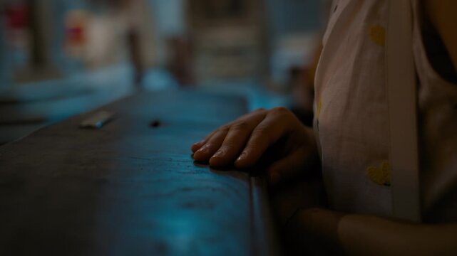 Relaxed hand resting on the polished wood of a church pew
