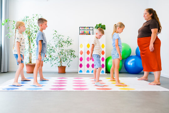 Kids practice mental arithmetic on a floor abacus with their teacher, combining counting with physical movement, concentration and coordination.