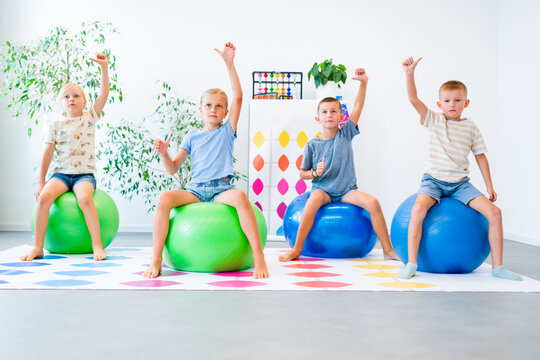 Kids practice mental arithmetic using abacus gestures while sitting on balance balls, combining calculation with motor exercises, concentration, coordination and cognitive training.