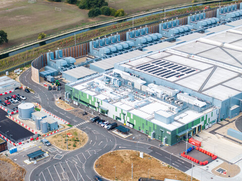 Aerial view of Google Data Centre in Waltham Cross, featuring large industrial buildings, cooling systems, parking areas, and surrounding green landscape in Cheshunt, England, United Kingdom.