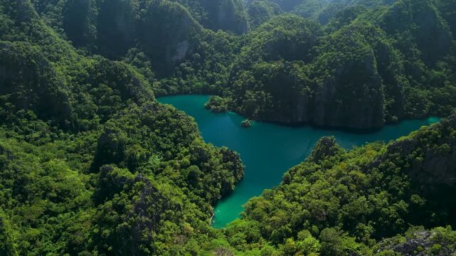 Aerial view of a turquoise tropical lagoon surrounded by lush green karst cliffs in Coron Palawan Philippines.