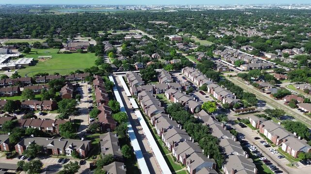 Sprawling apartment complexes border Parkway Boulevard near Mockingbird Elementary School. Lengthy covered carports, parked automobiles, lush green residential parks border Coppell, Texas.