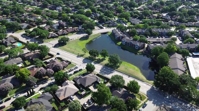 Retention ponds border Parkway Boulevard along Moore Road residential intersections. Winding suburban roads, expansive green shorelines, dense deciduous woodland border Coppell, Texas.