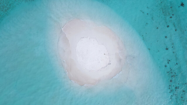 Aerial view of Pasir Timbul sandbar surrounded by crystal clear turquoise water in Raja Ampat, Papua Barat Daya, Indonesia.