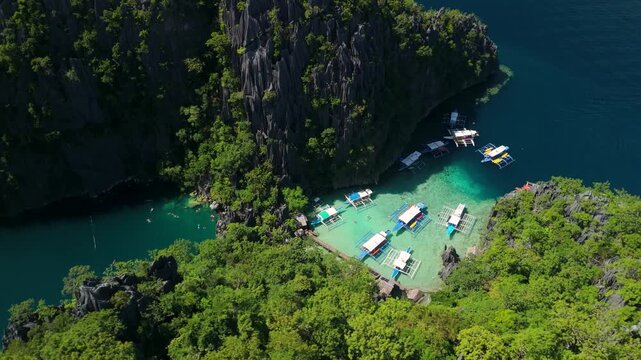 Aerial view of turquoise lagoon with outrigger boats and limestone cliffs in Coron Palawan Philippines.