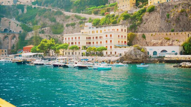 Marina full of small boats below a long white seafront building in Amalfi