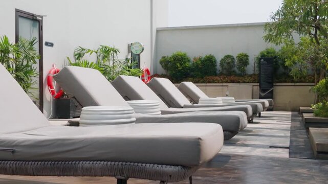 Row of comfortable sun loungers by the poolside at a luxury modern hotel resort.