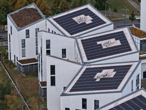 Aerial view of modern white residential buildings with solar panels on slanted roofs in the Adlershof district of Berlin, Berlin, Germany.