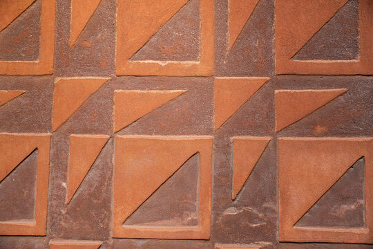 Geometric sgraffito pattern on a brown and orange exterior wall facade.