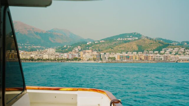 Seaside Salerno city stretching below dry ridges beyond a boat rail
