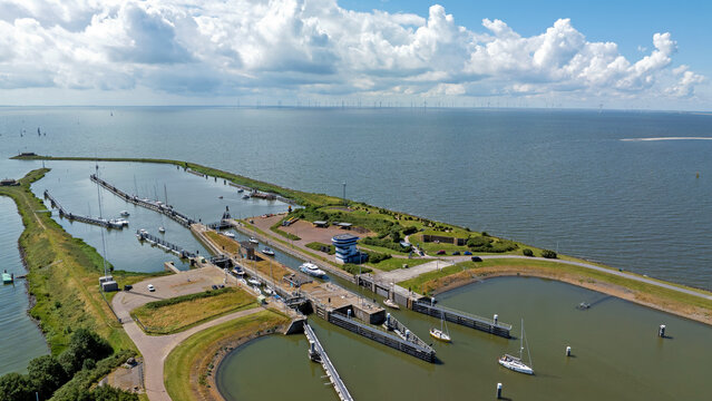 Aerial view of the Lorentzsluizen lock complex at the Afsluitdijk with boats in the waterway, surrounded by green embankments in Kornwerderzand, Friesland, Netherlands.