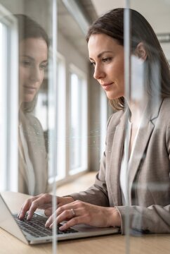 Businesswoman typing beside reflective window