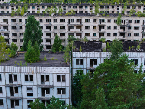 Aerial view of the abandoned Soviet military ghost town of Irbene, featuring decaying residential buildings overgrown with trees and vegetation in Irbene, Ventspils Municipality, Latvia.