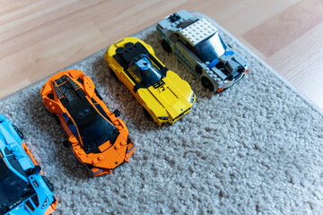 Obraz premium Warsaw, Poland - Sep 4, 2026: Row of LEGO Technic model cars in blue, orange, yellow and white on a gray rug