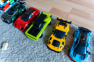 Obraz premium Warsaw, Poland - Sep 4, 2026: Row of LEGO Technic model cars in green, red, yellow and blue on a gray rug