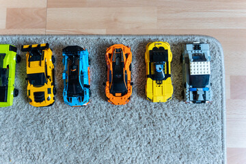 Obraz premium Warsaw, Poland - Sep 4, 2026: Row of seven LEGO Technic model cars lined up on a gray carpet near a wooden floor